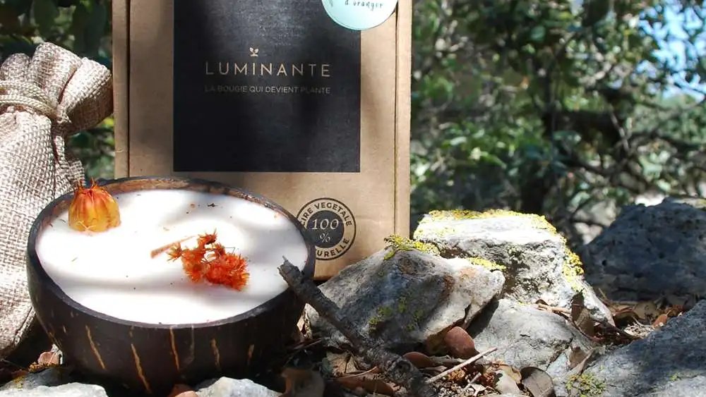 Bougie Luminante et sa boîte posées sur des rochers en pleine nature