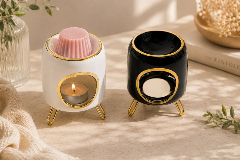 Deux brûle-parfums en céramique Luminante, un blanc contenant un fondant rose et un noir
