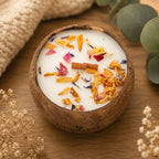 Bougie Luminante Fruits Exotiques dans son contenant en noix de coco, fleurs séchées orange et bleues sur la cire
