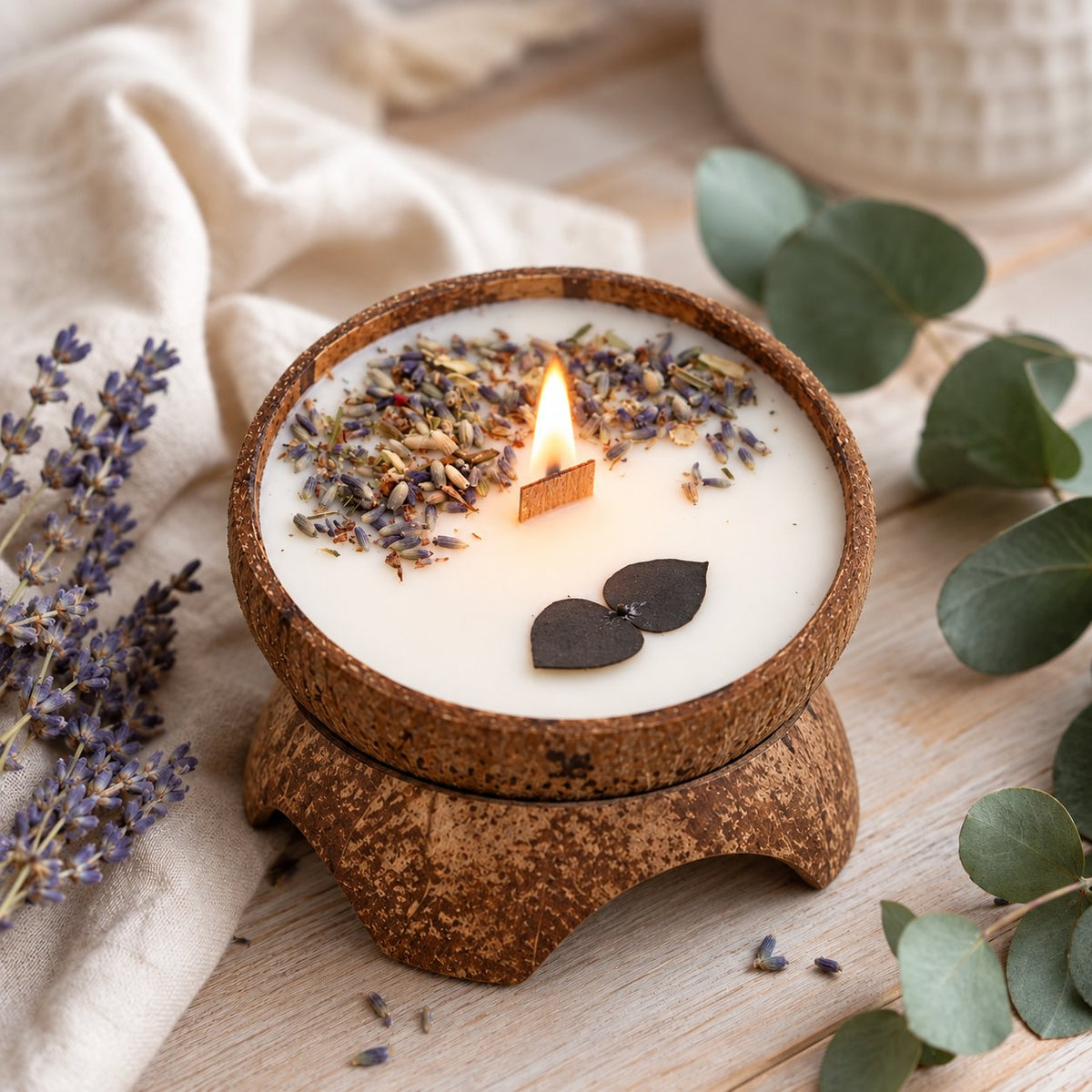 Bougie Luminante Eucalyptus Lavande allumée, brins de lavande séchée et feuilles noires en cire sur le dessus