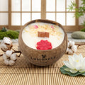Bougie Luminante Lotus blanc coton posée sur une natte de bambou, avec fleur de lotus et branche de coton