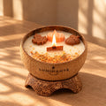Bougie Luminante Pumpkin Spice allumée dans sa coque en noix de coco, posée sur son socle en coco