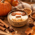 Bougie Luminante Pumpkin Spice dans son contenant en noix de coco, décorée d’une feuille d’érable, d’une citrouille et d’un gland en cire, entourée de cannelle, de badiane et de tranches d’orange séchées