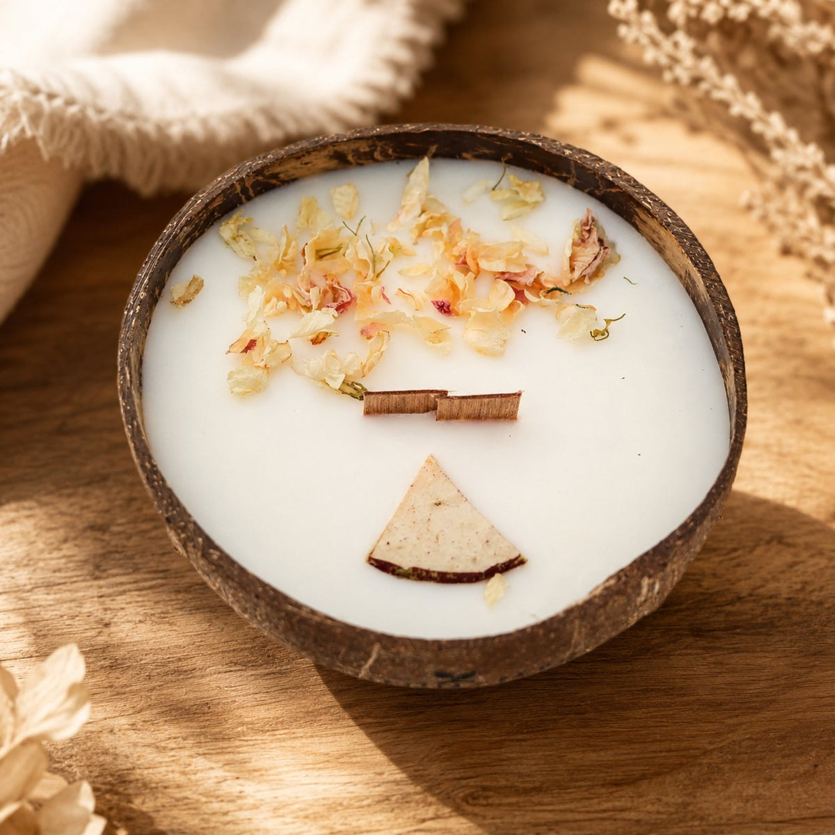 Bougie Luminante Pomme d'Amour dans son contenant en noix de coco, pétales séchés et tranche de pomme