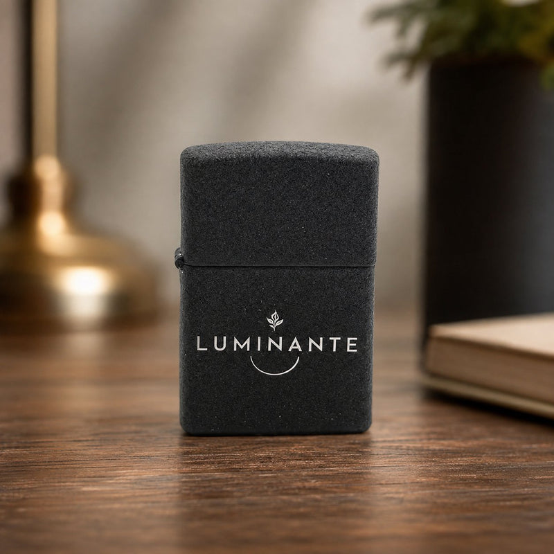 Briquet Luminante noir mat fermé, logo gravé, posé sur une table en bois