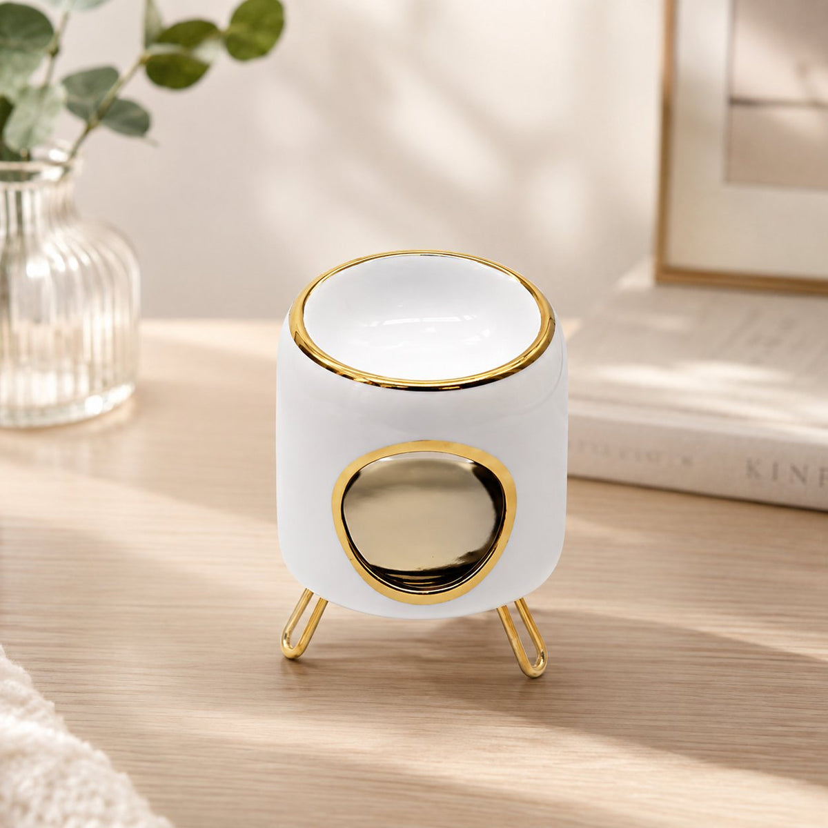 Brûle-parfum Luminante en céramique blanche à lisersé doré, sur ses pieds métalliques