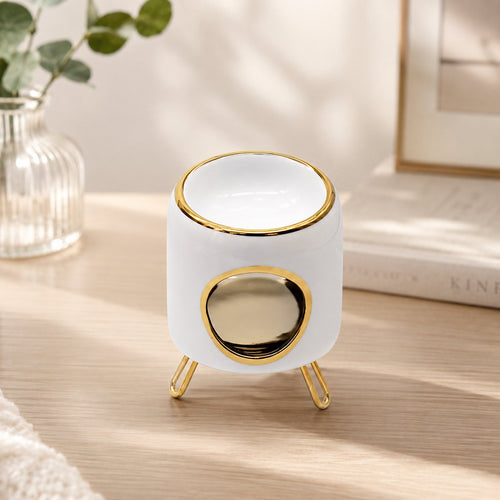 Brûle-parfum Luminante en céramique blanche à lisersé doré, sur ses pieds métalliques