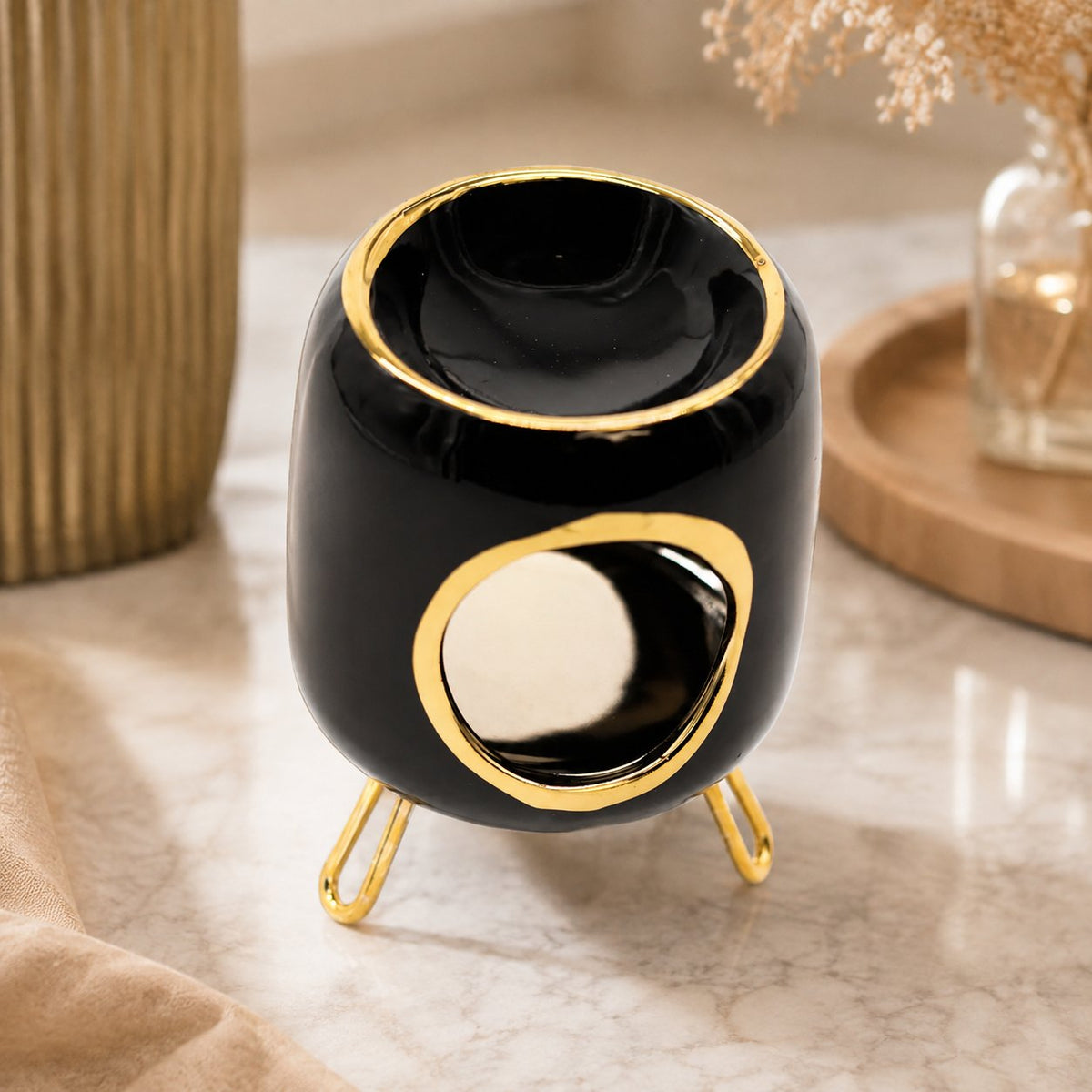 Brûle-parfum Luminante en céramique noire laquée à lisersé doré, sur ses pieds métalliques