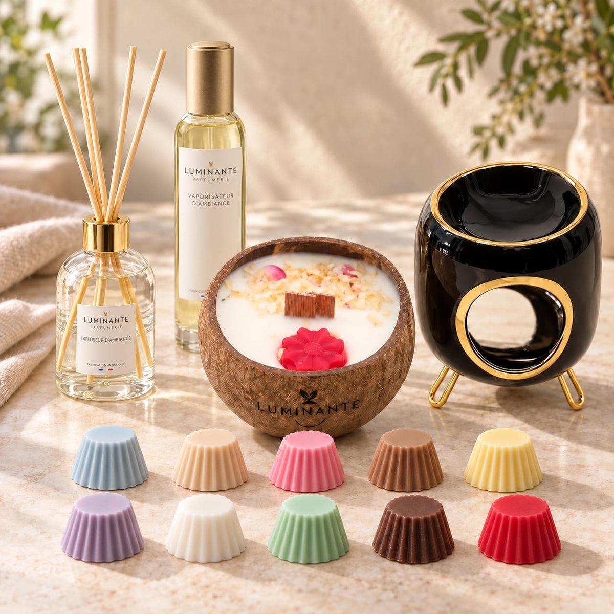 Coffret cadeau Luminante Grande Évasion : un diffuseur d'ambiance et ses bâtonnets, un vaporisateur, une bougie parfumée en noix de coco, un brûle-parfum noir et or et dix fondants parfumés