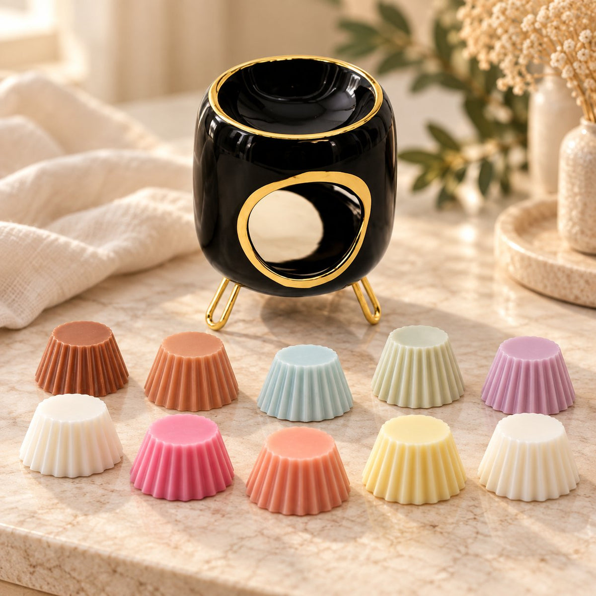 Coffret cadeau Luminante Odyssée olfactive : un brûle-parfum en céramique noire et dorée et dix fondants parfumés de couleurs variées