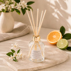 Diffuseur d'ambiance Luminante Fleur d'oranger-Bergamote sur un plateau en pierre, avec fleurs d'oranger et agrumes coupés