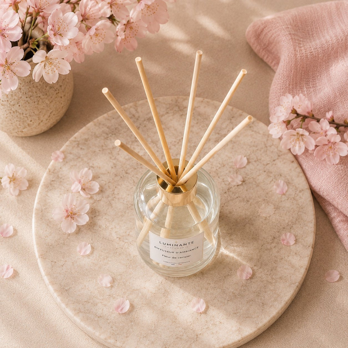 Diffuseur d'ambiance Luminante Fleur de cerisier vu de dessus sur un plateau, pétales roses éparpillés