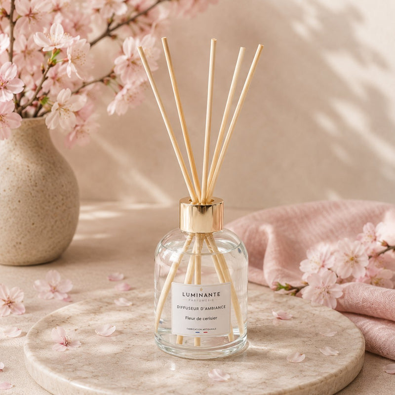 Diffuseur d'ambiance Luminante Fleur de cerisier, entouré de branches de cerisier en fleurs et de pétales roses