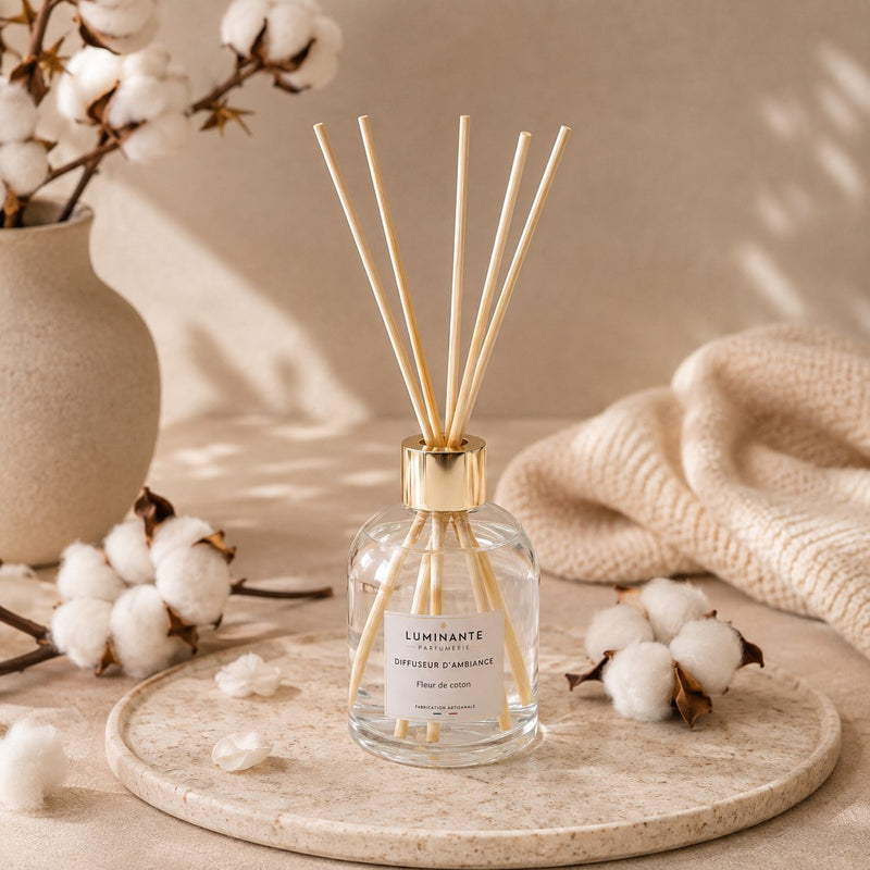Diffuseur d'ambiance Luminante Fleur de coton sur un plateau, entouré de branches de coton et d'un plaid écru