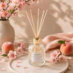 Diffuseur d'ambiance Luminante Pêcher fleuri, entouré de fleurs de pêcher roses et de pêches mûres