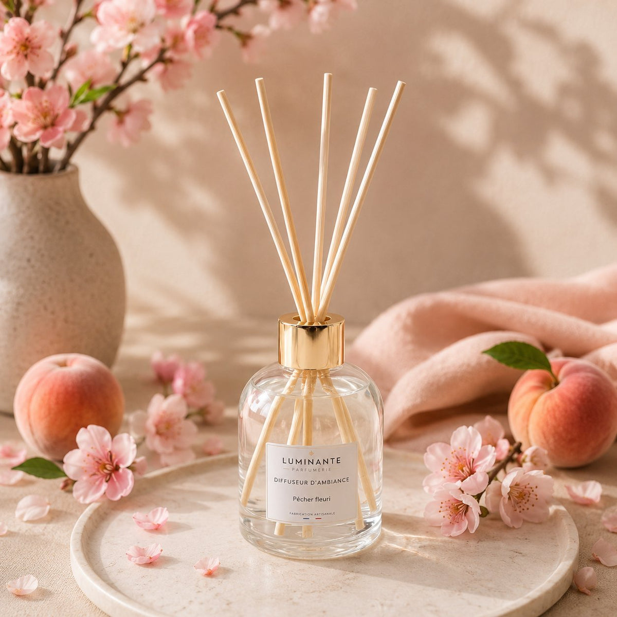 Diffuseur d'ambiance Luminante Pêcher fleuri, entouré de fleurs de pêcher roses et de pêches mûres