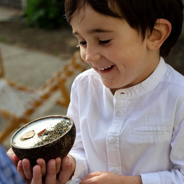 Enfant souriant tenant une bougie Luminante en coque de noix de coco