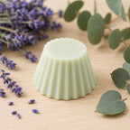 Fondant parfumé Luminante Eucalyptus Lavande posé sur un plan en bois clair, entre un bouquet de lavande et des branches d'eucalyptus