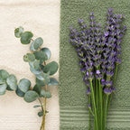Branche d'eucalyptus et bouquet de lavande posés sur des serviettes éponge écrue et vert sauge