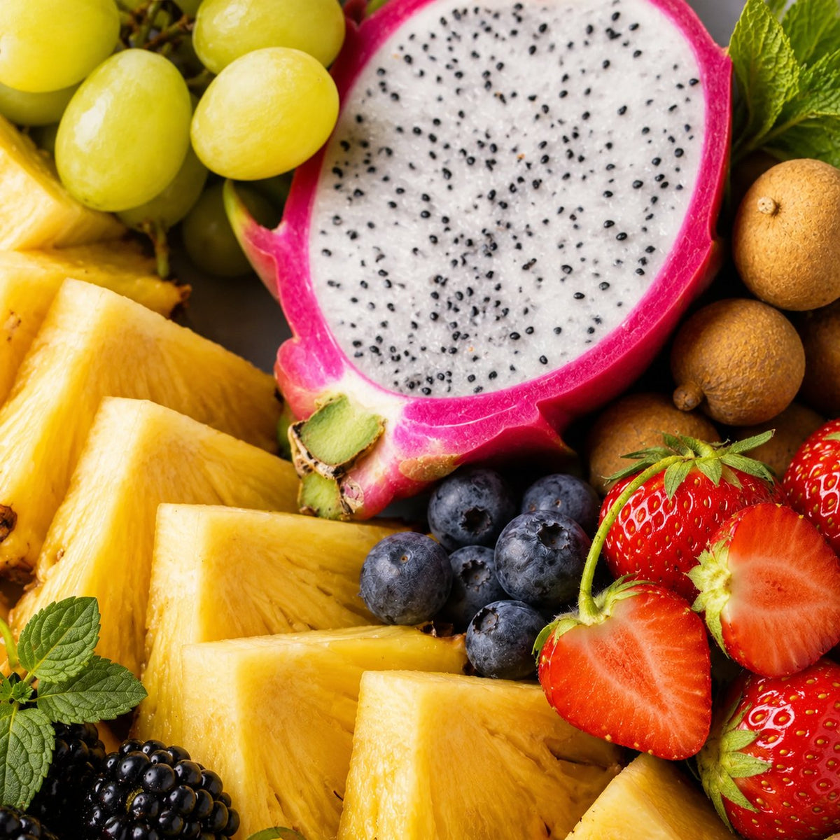 Assortiment de fruits frais : ananas, fruit du dragon, raisin, fraises, myrtilles et litchis