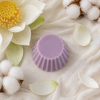 Fondant parfumé Luminante Lotus blanc coton vu de dessus sur un voile écru, avec une fleur de lotus ouverte et des branches de coton