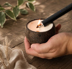 Briquet rechargeable du kit Luminante allumant la mèche en bois d'une bougie tenue dans la main