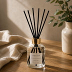 Bâtonnets noirs Luminante déployés dans un flacon de diffuseur d'ambiance, sur un meuble en bois