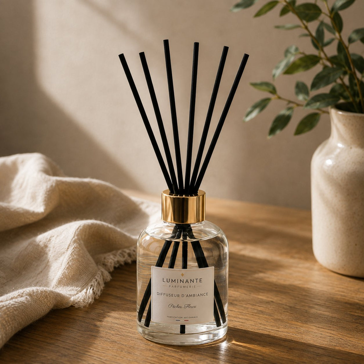 Bâtonnets noirs Luminante déployés dans un flacon de diffuseur d'ambiance, sur un meuble en bois