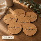 Les six dessous en liège Luminante disposés en rosace sur une table en bois, chacun gravé du logo de la marque