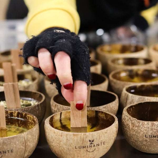 Main gantée plaçant la mèche dans une coque de noix de coco à l'atelier