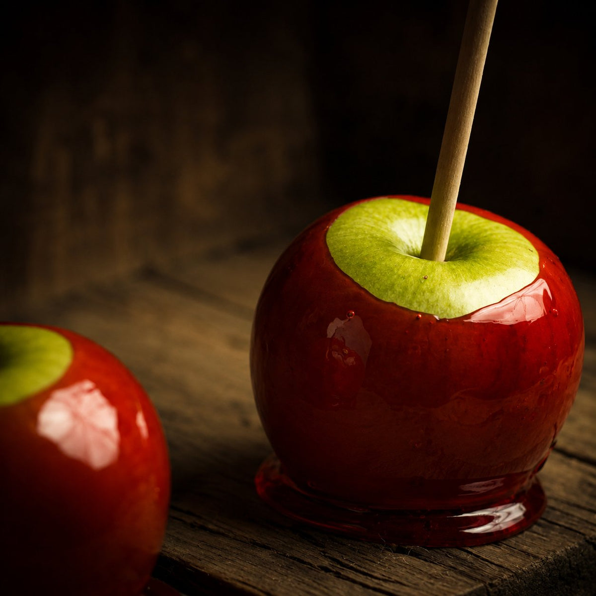 Deux pommes d'amour rouges brillantes sur un plateau en bois