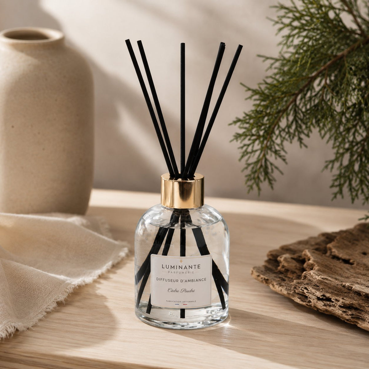 Diffuseur d'ambiance Luminante Cèdre poudré et ses bâtonnets, sur une table en bois clair