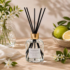 Diffuseur d'ambiance Luminante et ses bâtonnets, entouré de fleurs d'oranger et d'agrumes