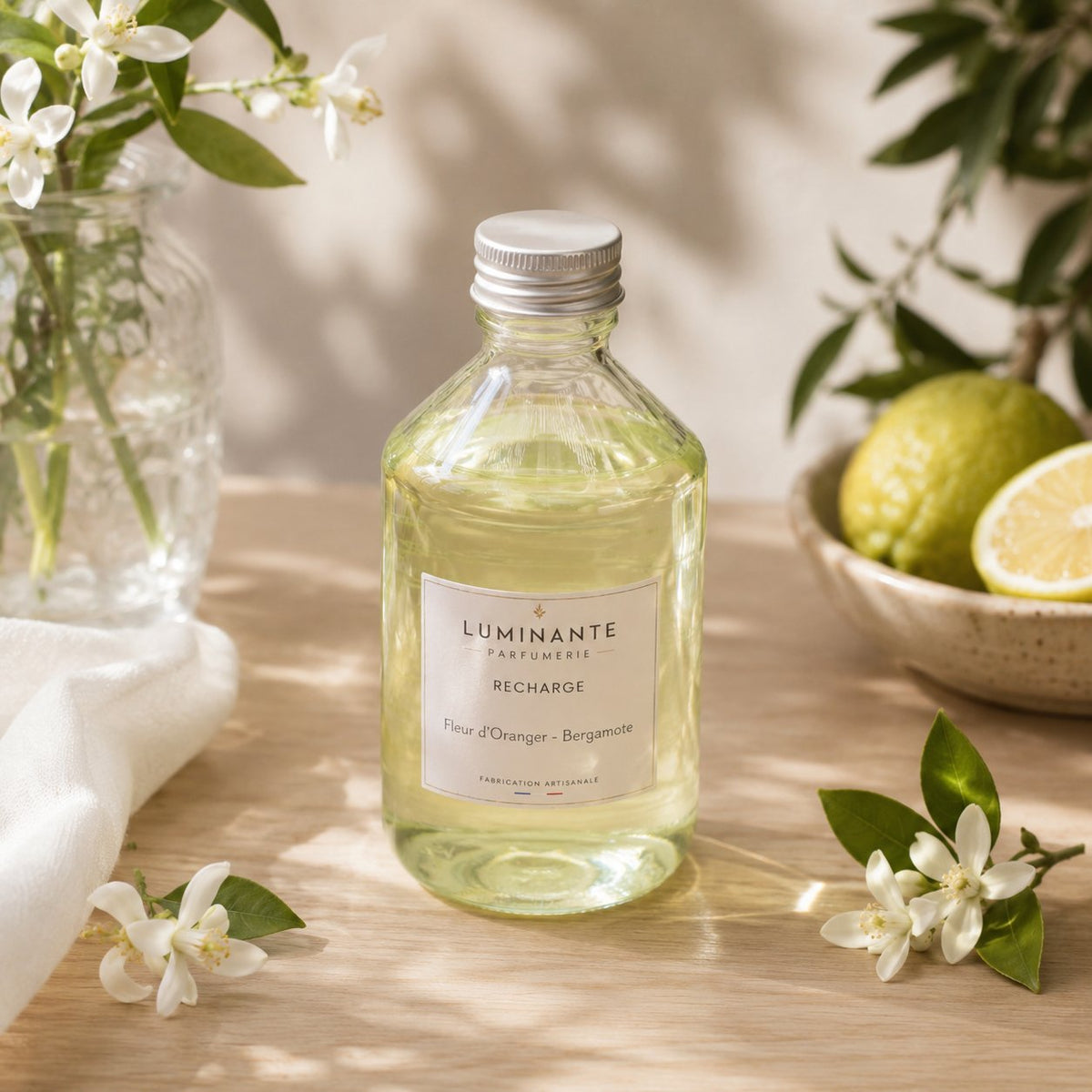 Recharge Luminante Fleur d'Oranger-Bergamote, flacon en verre entouré de fleurs d'oranger et d'agrumes
