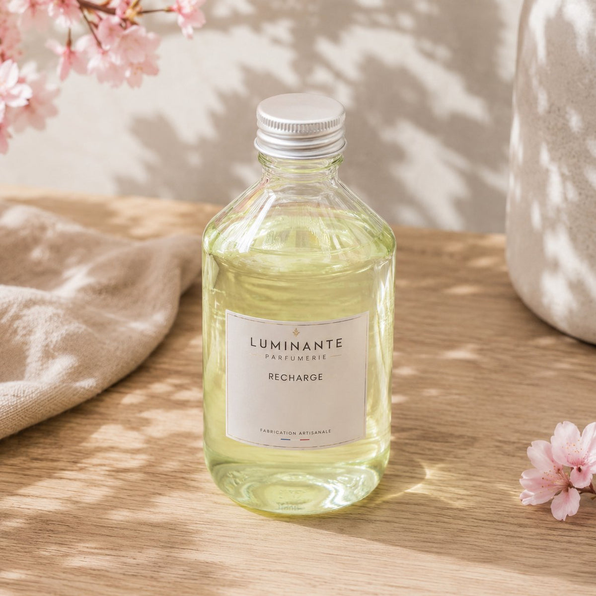 Recharge Luminante Fleur de cerisier, flacon en verre sous une branche de cerisier en fleurs