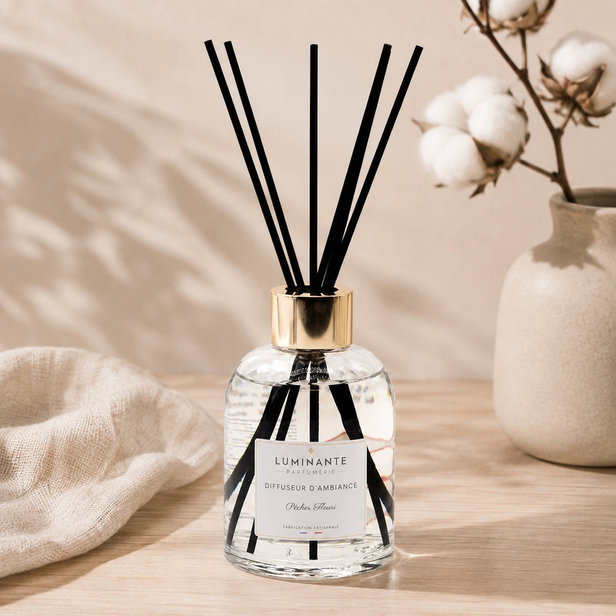 Diffuseur d'ambiance Luminante et ses bâtonnets, près d'un bouquet de coton séché