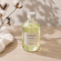 Recharge Luminante Fleur de coton, flacon en verre près d'une branche de coton séché