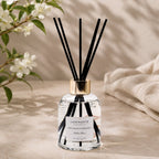 Diffuseur d'ambiance Luminante et ses bâtonnets, entouré de fleurs de jasmin blanches