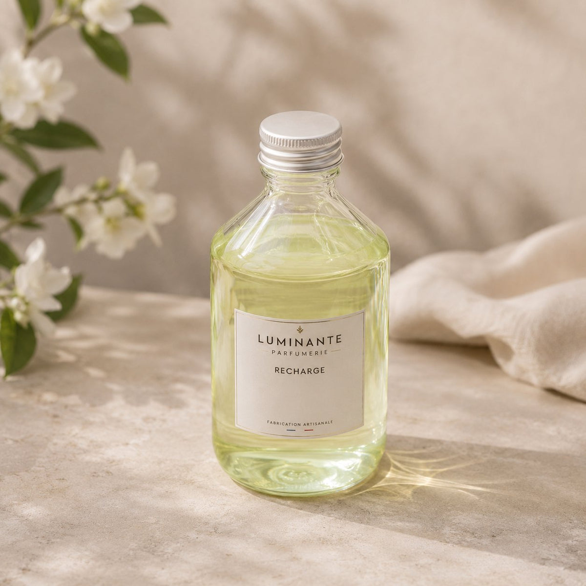 Recharge Luminante Jasmin-Cachemire, flacon en verre entouré de fleurs de jasmin blanches