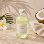 Recharge Luminante Tiaré-Coco, flacon en verre entre des fleurs de tiaré et une noix de coco ouverte