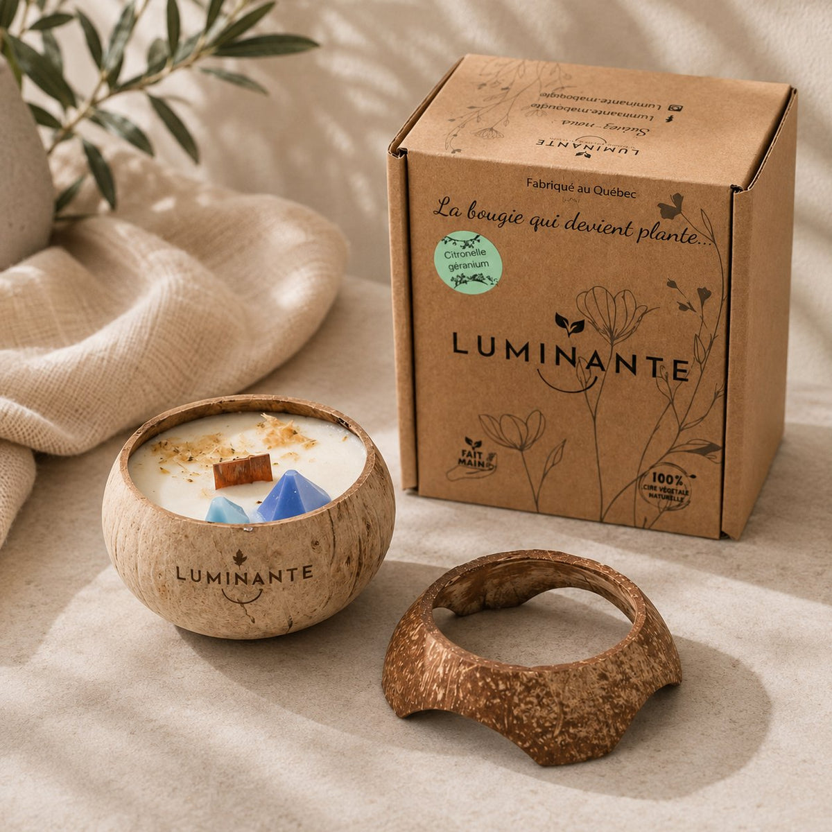 Bougie Luminante allumée sur son socle en coco, à côté de sa boîte kraft