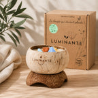 Bougie Luminante en noix de coco posée sur son socle, avec sa boîte kraft