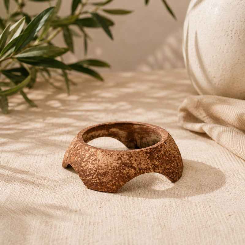 Socle Luminante en coco pour bougie, posé seul sur une nappe en lin écru