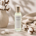Vaporisateur d'ambiance Luminante Fleur de coton, flacon à bouchon doré près de fleurs de coton