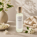 Vaporisateur d'ambiance Luminante Jasmin-Cachemire, flacon à bouchon doré entouré de fleurs de jasmin